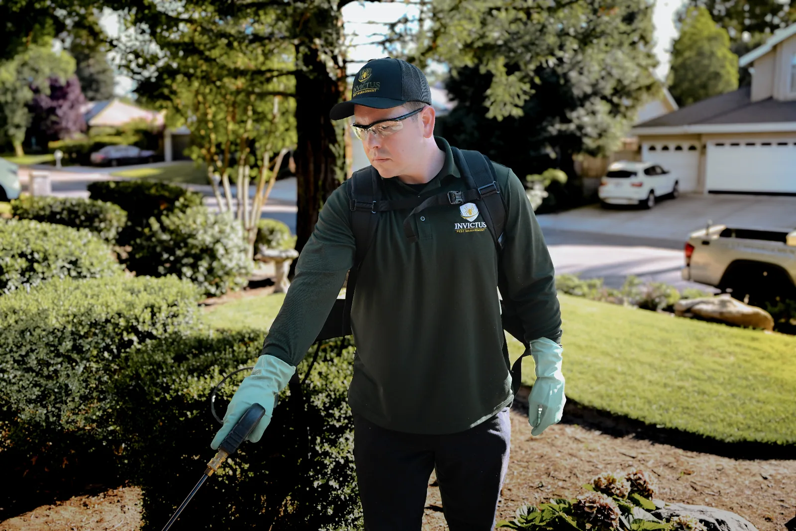 Invictus Pest Management technician treating landscaping outside a Central Valley home